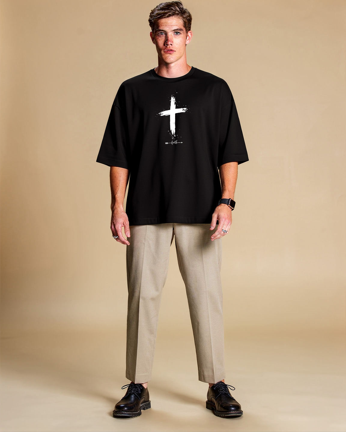Man wearing a black t-shirt with a white cross design on a beige background