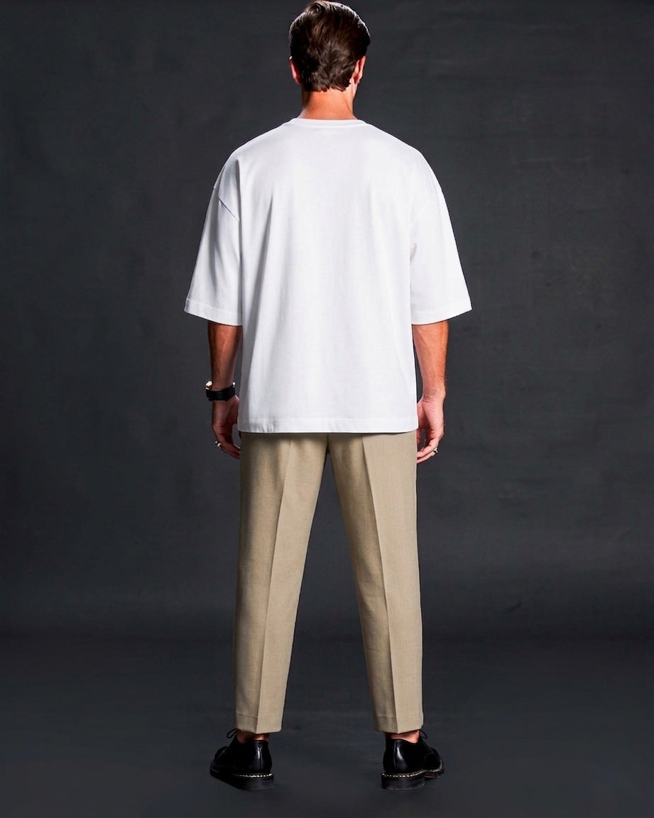 Person wearing a white t-shirt and beige pants against a dark background