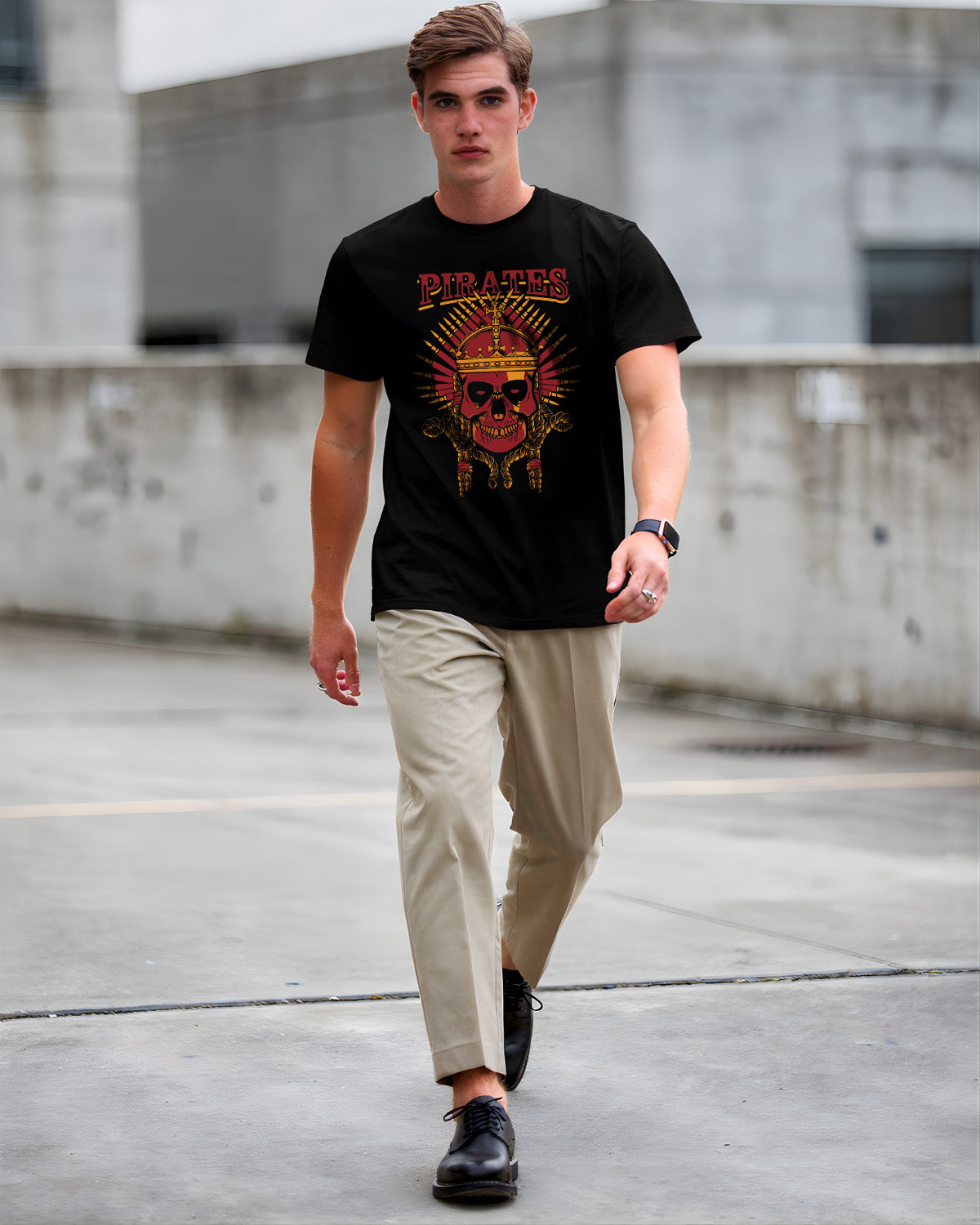 Man wearing a black graphic t-shirt with beige pants and black shoes in an urban setting.