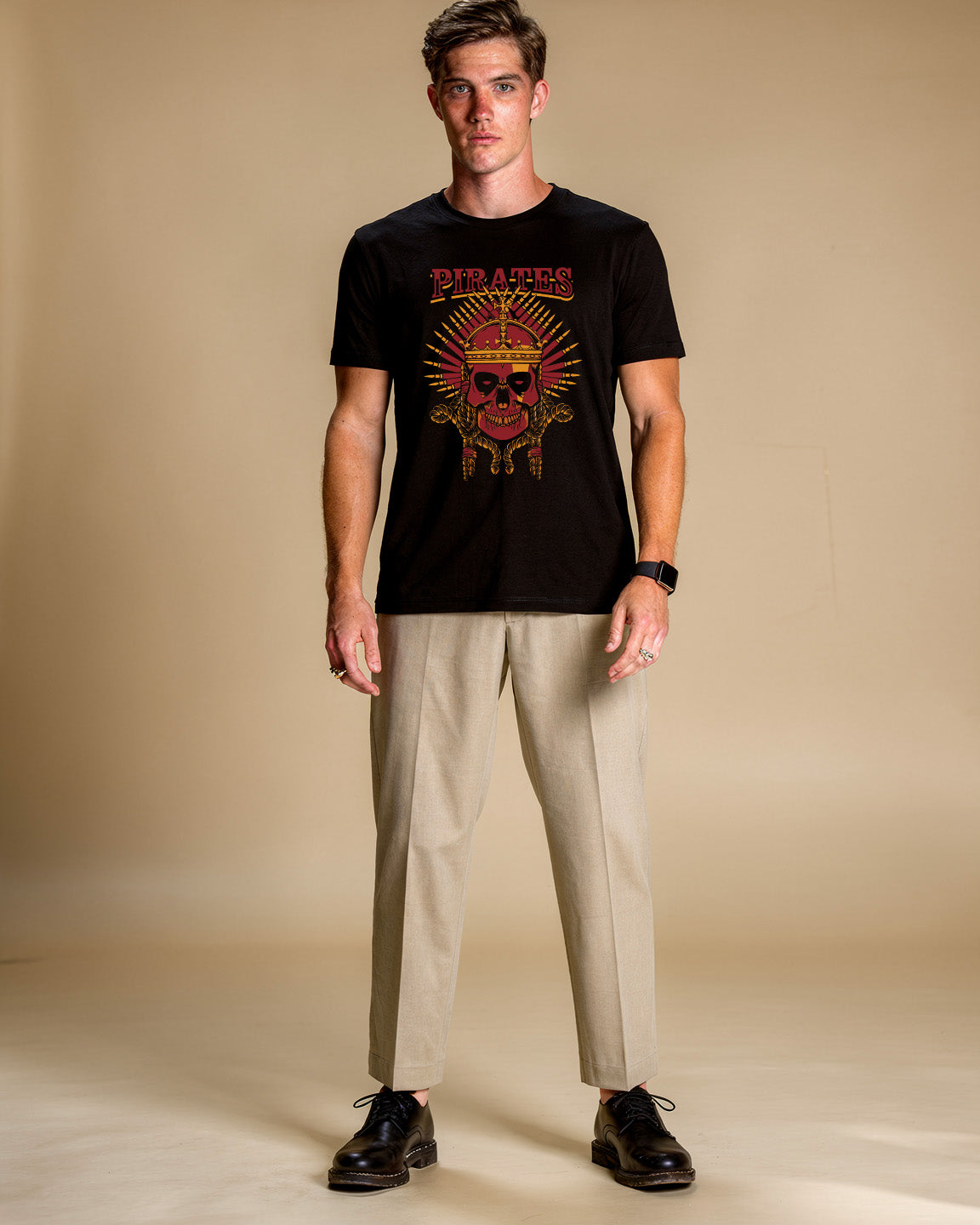 Man wearing a black t-shirt with a skull design and text, standing against a beige background