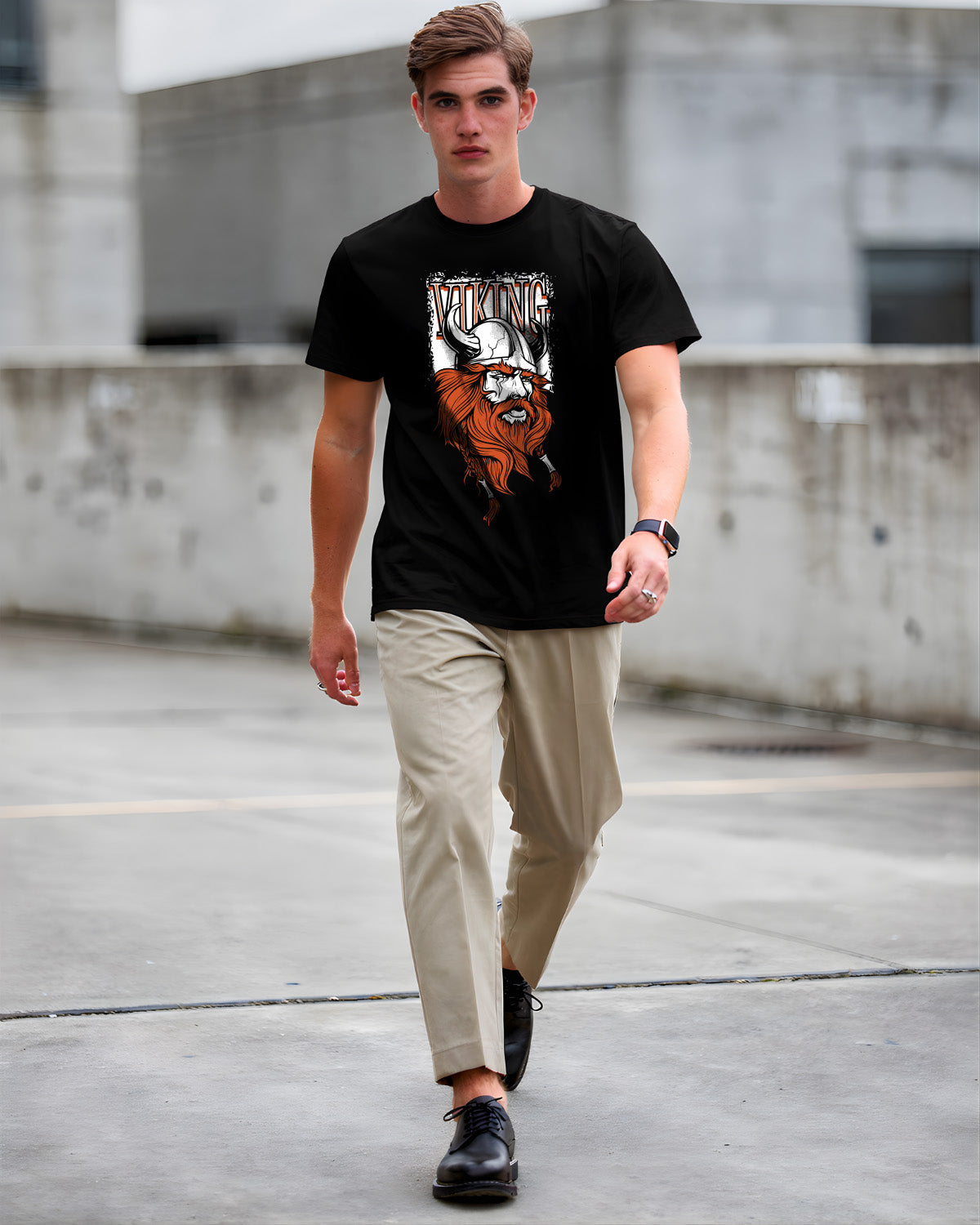 Man wearing a black t-shirt with a graphic design, beige pants, and black shoes in an urban setting.