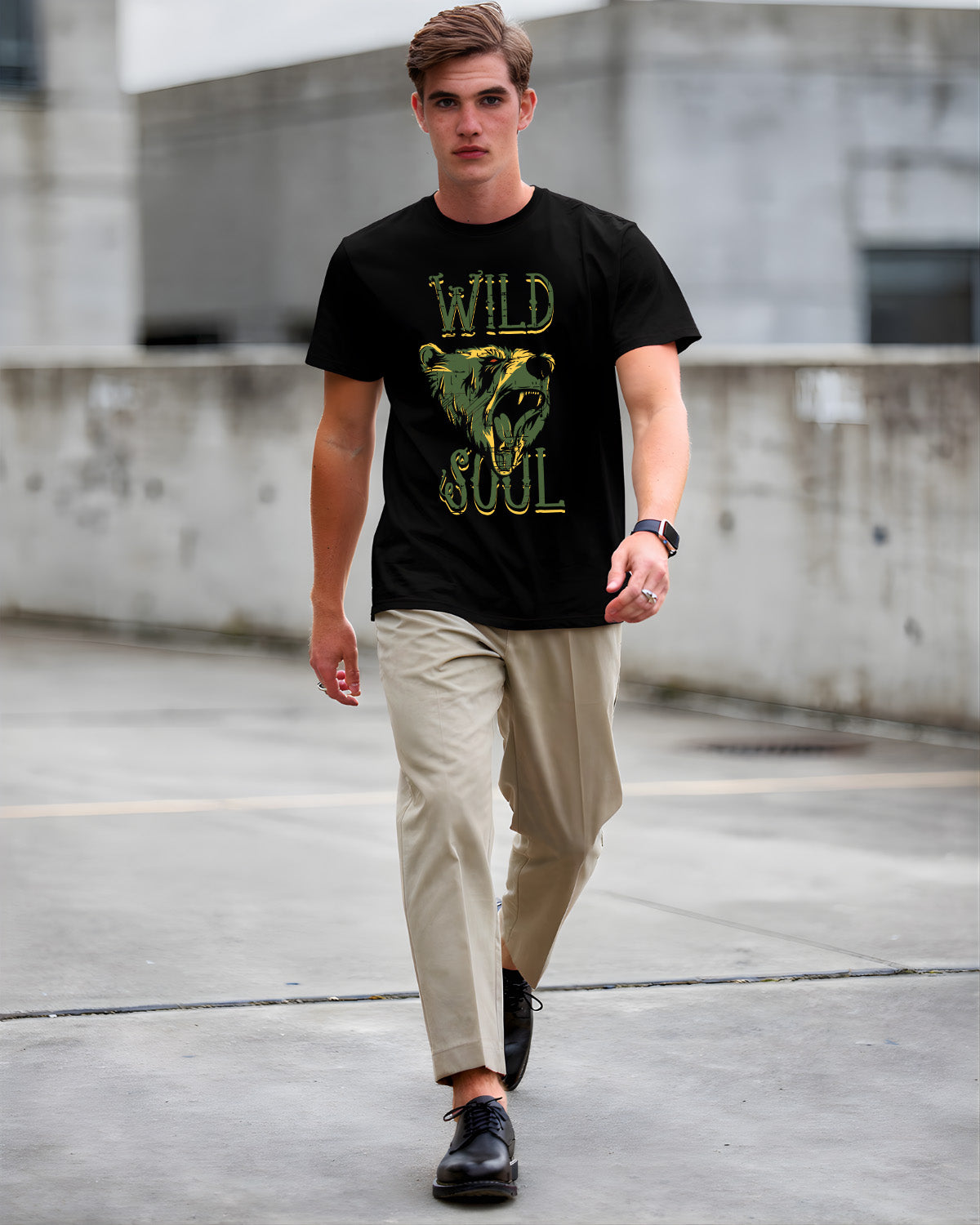 Man wearing a black t-shirt with 'Wild Soul' graphic and beige pants walking on a concrete surface.