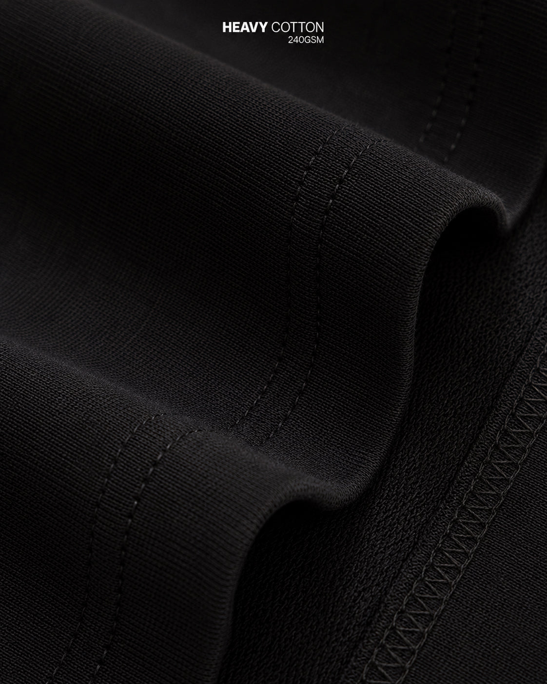 Close-up of black fabric with 'Heavy Cotton 240 GSM' text