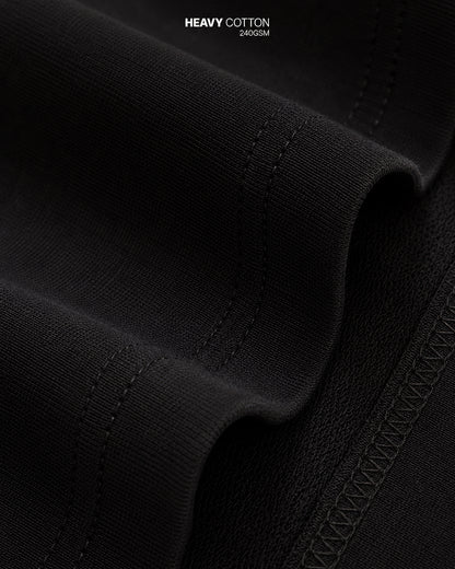 Close-up of black fabric with 'Heavy Cotton 240 GSM' text