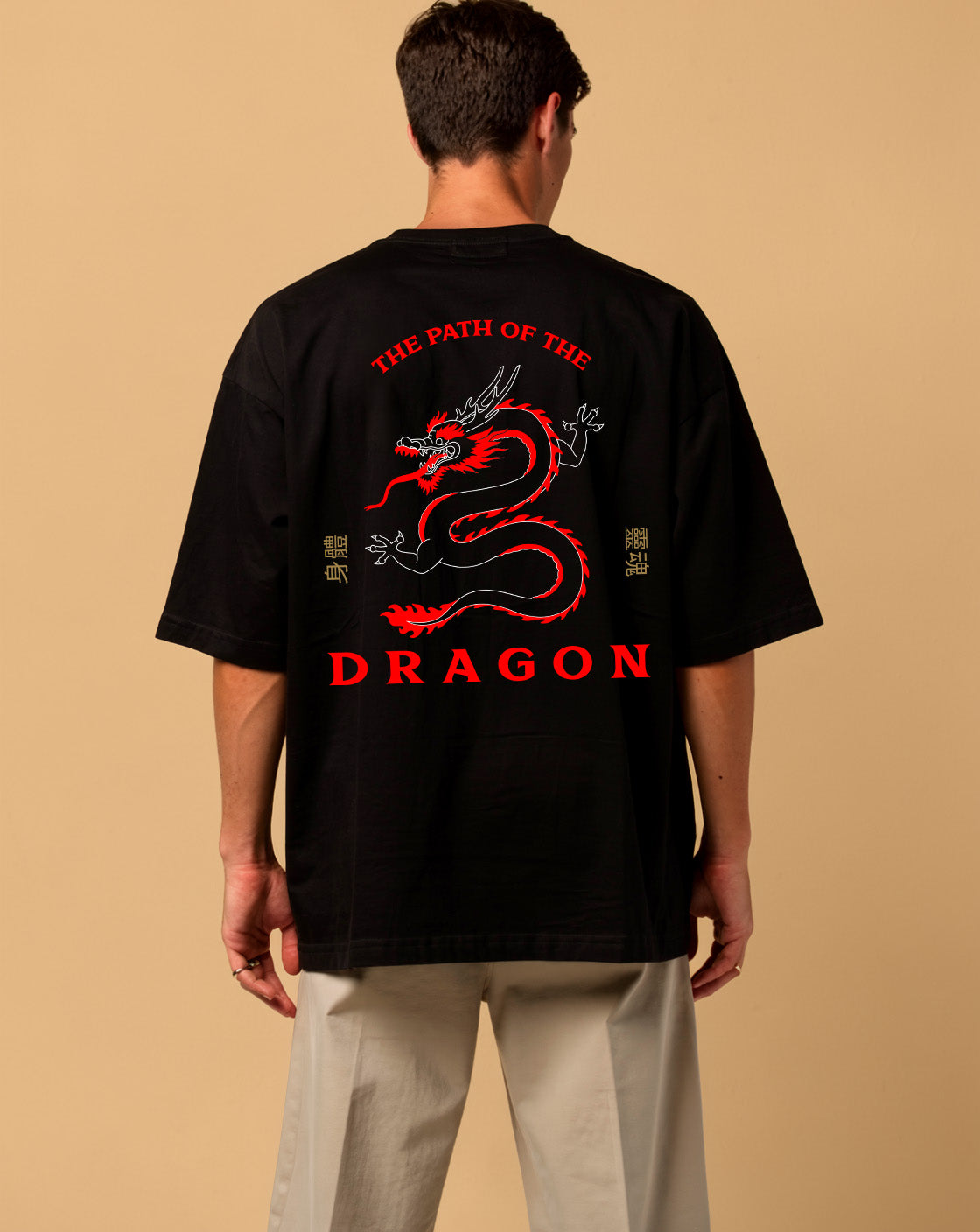 Person wearing a black t-shirt with a red dragon design and text on the back, against a beige background
