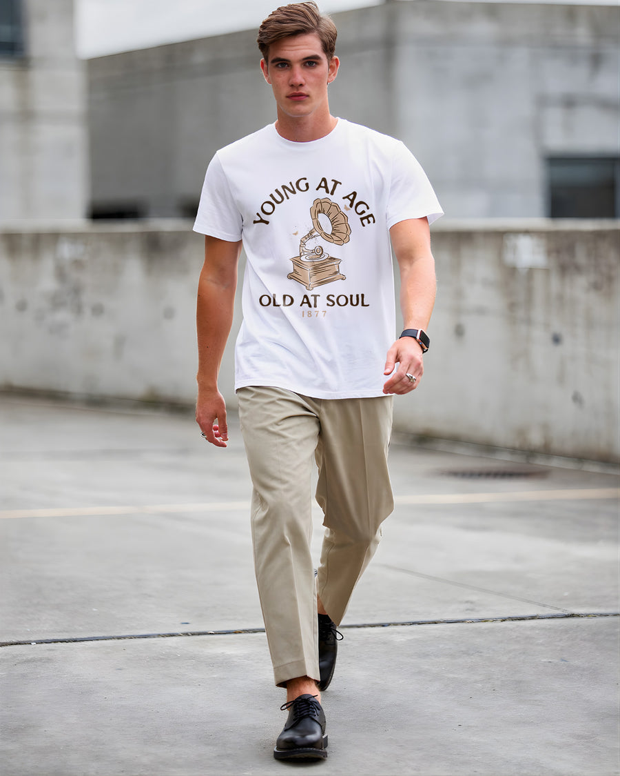 Man wearing a white t-shirt with text and graphics, walking on a concrete surface.